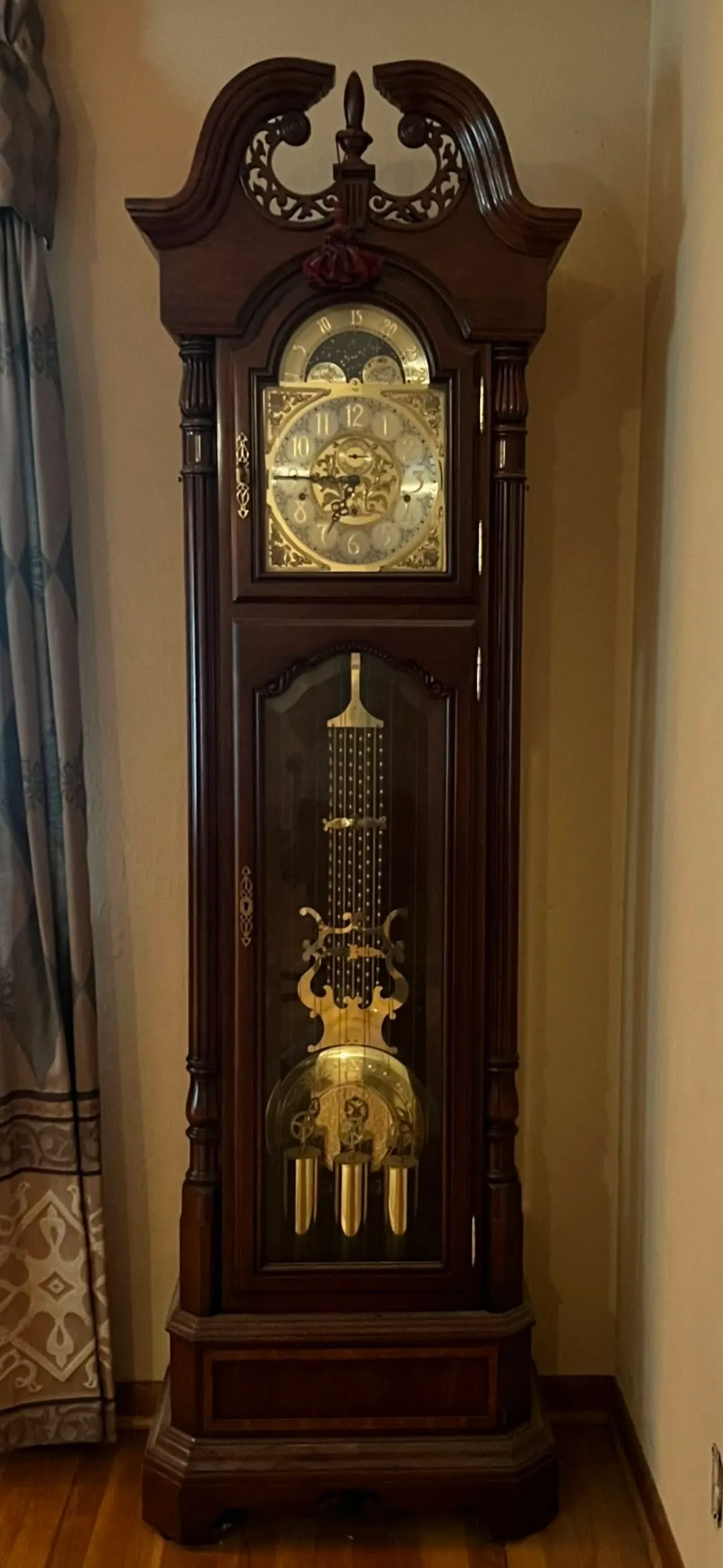 Elegant mahogany grandfather clock with broken-pediment crown, moon-phase dial and lyre pendulum